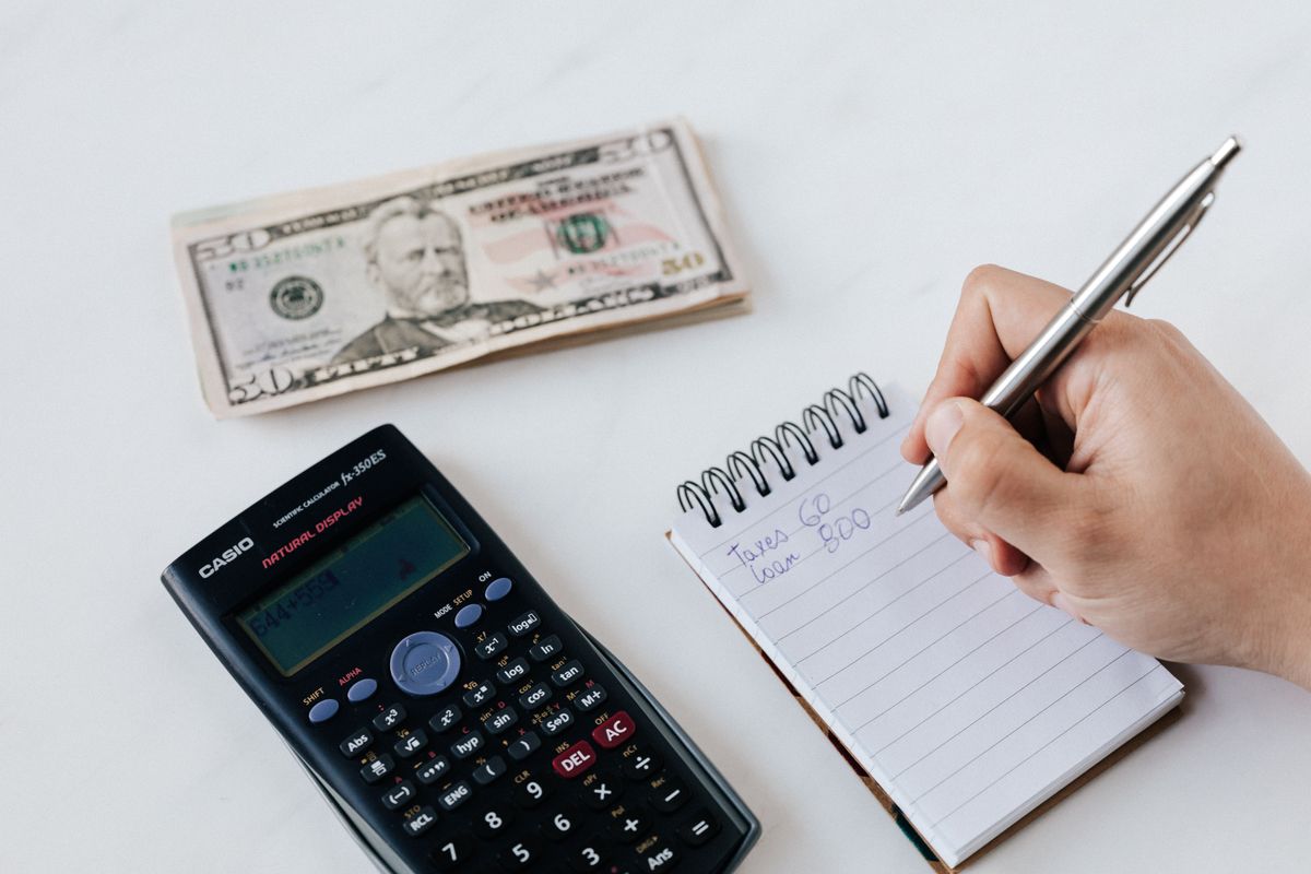 A person writing beside a calculator