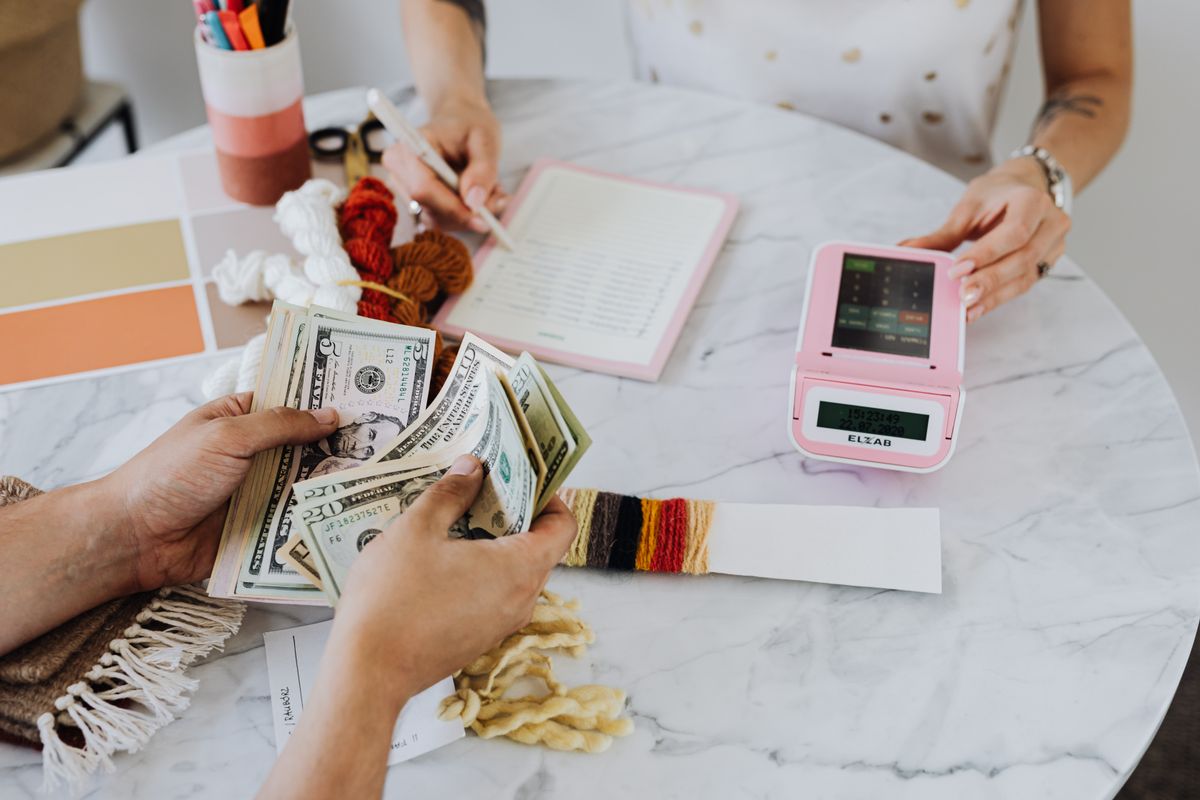 People counting cash beside a notebook